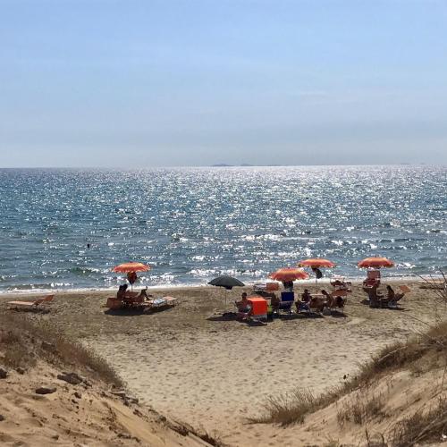 a group of people sitting on a beach with umbrellas at Climbing House Chèrie Madeleine in Lido Di Fondi