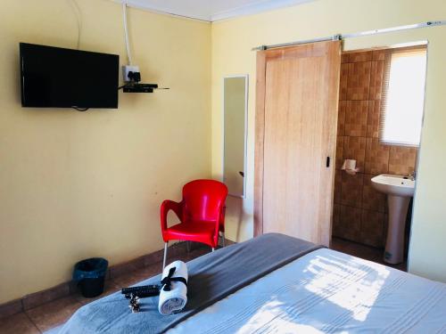 a bedroom with a bed and a red chair at Maite Villa Lodge in Thohoyandou