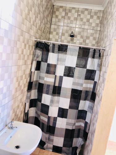 a bathroom with a shower curtain and a sink at Maite Villa Lodge in Thohoyandou
