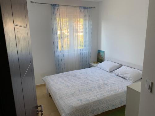 um quarto com uma cama branca e uma janela em Tamaris House Apartment 16 em Herceg Novi