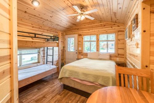 Dormitorio en cabaña de madera con cama y ventilador de techo en Mount Hood Village Deluxe Cabin 5, en Welches