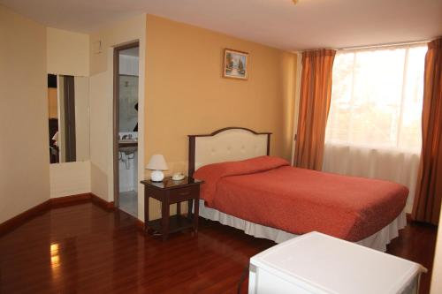a bedroom with a red bed and a window at Hotel Luxor in Cochabamba