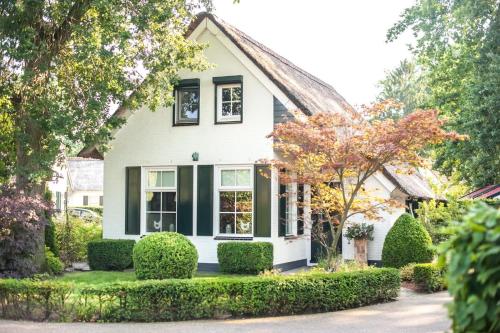 a white house with green trim and trees at Vakantiehuis Villa 63 in Heel