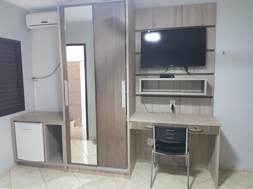 a room with a desk with a television and a chair at Hotel Nevada in Cascavel