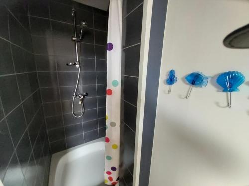 una ducha con lunares en el lateral de una bañera en Magnifique petit appartement tout équipé, silencieux en Anhée