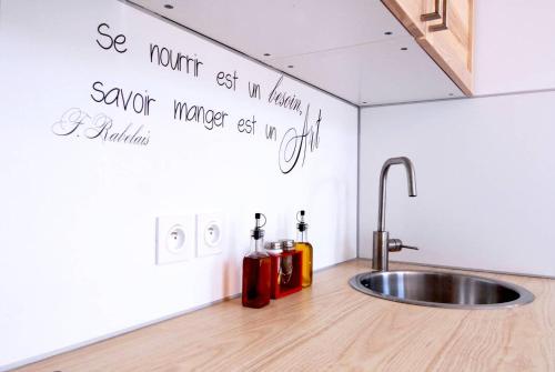 une cuisine avec un évier et une écriture sur le mur dans l'établissement 6 Couchages, Wifi Fibre & NETFLIX 
