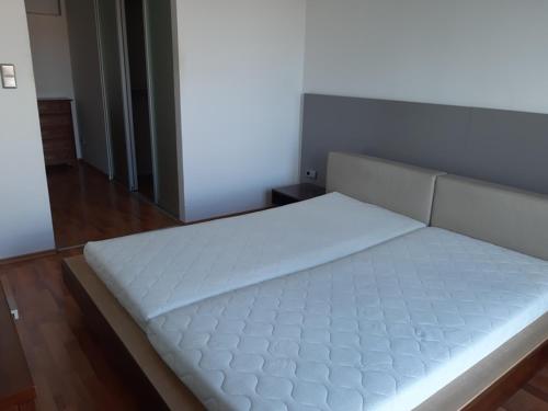 a large white bed in a room with wooden floors at Pleasant apartment under the Bratislava castle in Bratislava