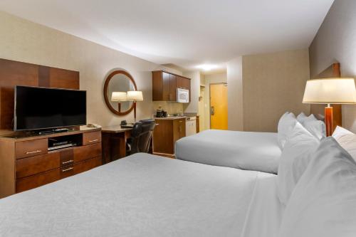 Habitación de hotel con 2 camas y TV de pantalla plana. en Devonian Hotel and Suites, en Fox Creek