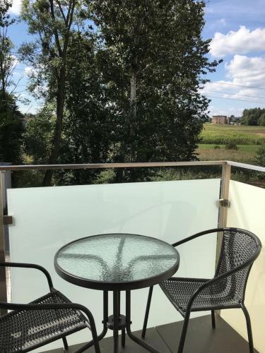 a glass table and two chairs on a balcony at Studio Fibra Lungo in Rybnik