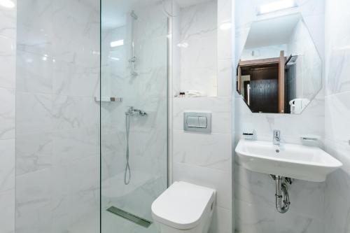 a white bathroom with a shower and a toilet and a sink at Hotel Pela in Ohrid