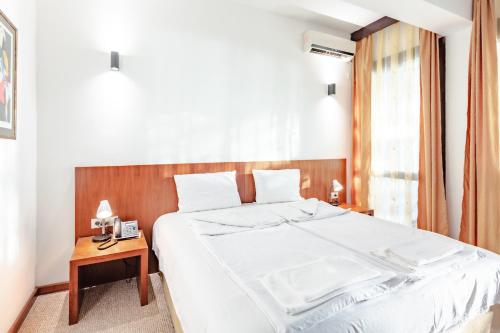 a bedroom with a large white bed and a table at Hotel Pela in Ohrid
