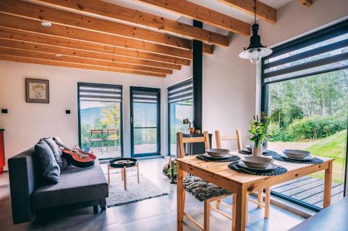 a living room with a table and chairs and windows at Domki 4 Nad Ranem - Baza Bieszczady Smerek in Smerek