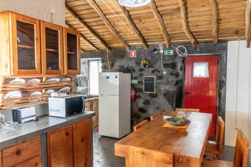 a kitchen with a wooden table and a refrigerator at Aldeia Dos Caldeirões in São Mateus