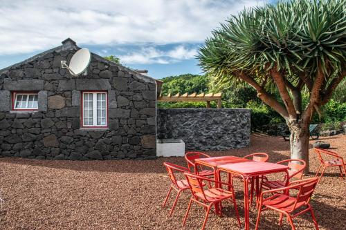 uma mesa vermelha e cadeiras em frente a um edifício de pedra em Aldeia Dos Caldeirões em São Mateus