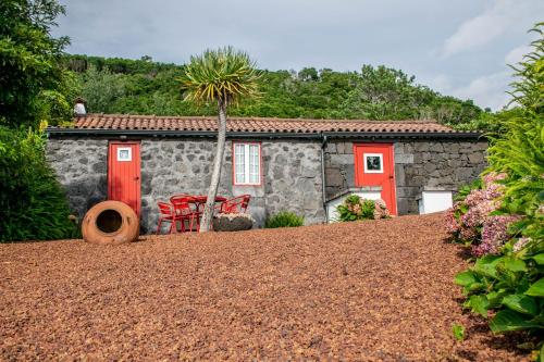 a stone house with red doors and a palm tree at Aldeia Dos Caldeirões in São Mateus