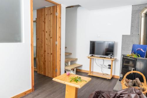 a living room with a tv and a table at Aldeia Dos Caldeirões in São Mateus