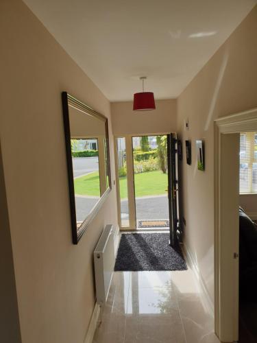 a hallway with a mirror and a door to a yard at Plantation Drive - Home from home in Limavady