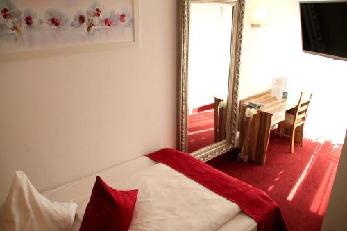 a bedroom with a mirror and a bed with red pillows at Hotel Bruckertshof in Bamberg
