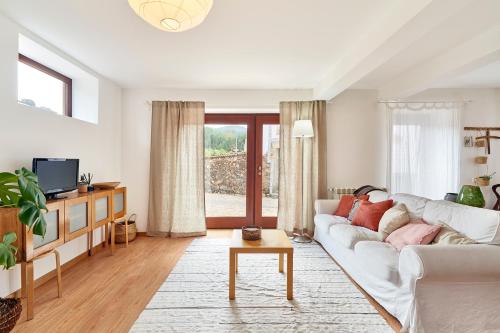 a living room with a white couch and a tv at Casa da Avó Amália in Janeiro de Cima