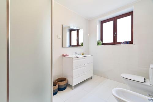 uma casa de banho branca com um lavatório e um espelho em Casa da Avó Amália em Janeiro de Cima
