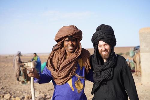 two men are walking in the desert at Bivouac Les Nomades & Foum zguid to chegaga tours in Foum Zguid