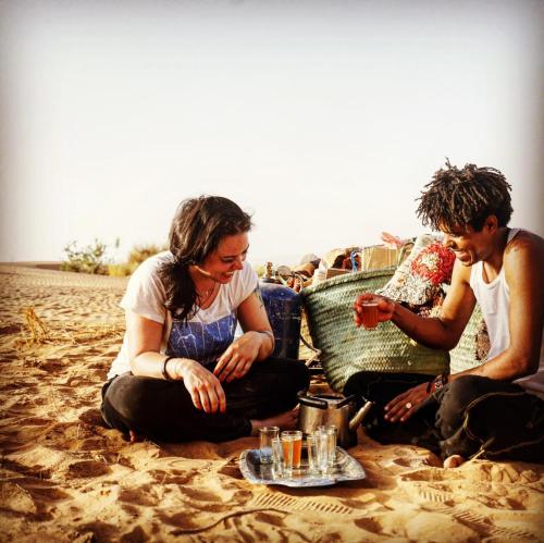 a group of people sitting on the beach at Bivouac Les Nomades & Foum zguid to chegaga tours in Foum Zguid