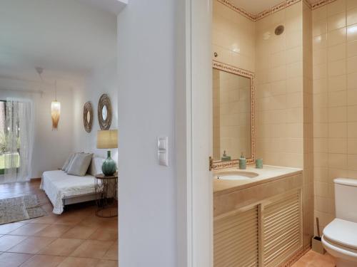 a bathroom with a sink and a toilet and a bedroom at Aroeira Golf - Beach House in Carcereiro