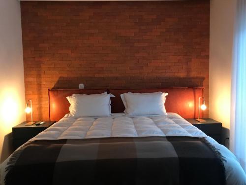 格拉馬杜的住宿－Austin Suites Gramado，一间卧室设有一张带砖墙的大床