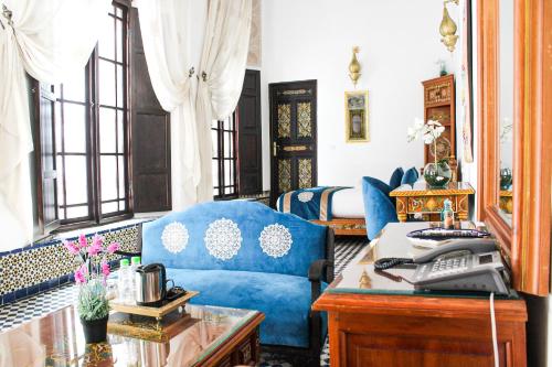 a living room with a blue couch and a desk at Le Grand Alcazar - Riad in Fès