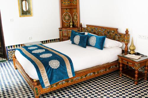 a bedroom with a bed with blue pillows and a table at Le Grand Alcazar - Riad in Fès