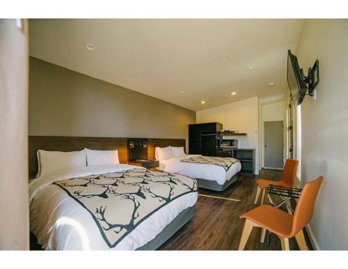 una habitación de hotel con 2 camas y una silla en Terra Nova Cabins en West Yellowstone