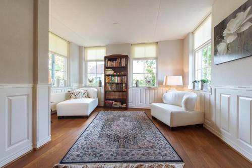 a living room with two white chairs and a rug at Vakantiehuis Villa 63 in Heel