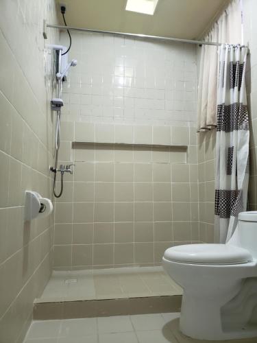 a bathroom with a shower and a toilet in it at Old Orangewood Bed & Breakfast in Baguio