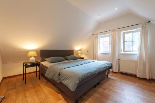 um quarto com uma cama grande e 2 janelas em Vakantiehuis Villa 63 em Heel
