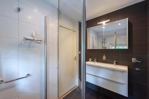 a bathroom with a shower and a sink and a mirror at Vakantiehuis Villa 63 in Heel