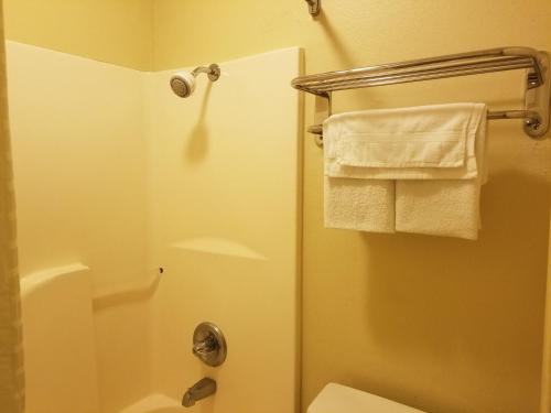 ein Bad mit einer Dusche, einem WC und Handtüchern in der Unterkunft Stay Inn Checotah in Checotah