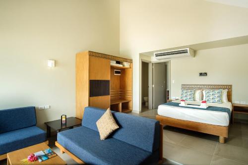 a bedroom with a bed and a blue couch at Plantation Island Resort in Malolo Lailai