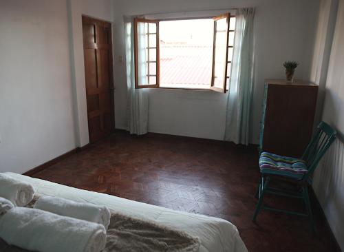 a bedroom with a bed and a chair and a window at Casa Los Jazmines in Sucre
