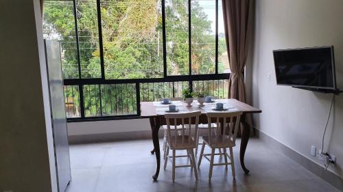 a dining room table with chairs and a large window at Residencial Vila das Canoas in Bombinhas