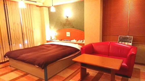 a bedroom with a bed and a red chair at HOTEL CIMA Ⅱ ( Adult Only ) in Kotohira