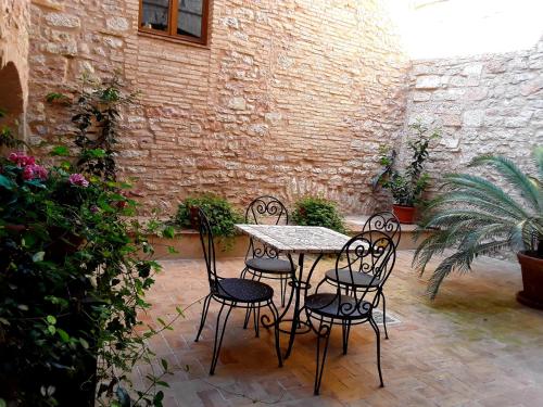 a table and chairs in a courtyard with a brick wall at Case Brizi 10 in Assisi