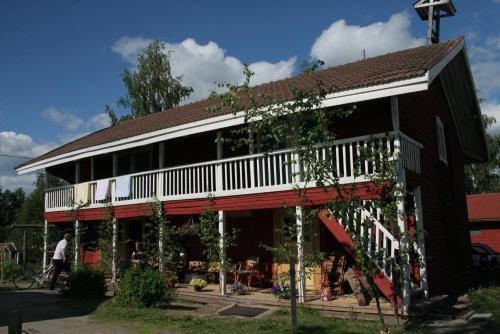 a brown building with a porch and a tree at Herranniemi Guesthouse in Vuonislahti