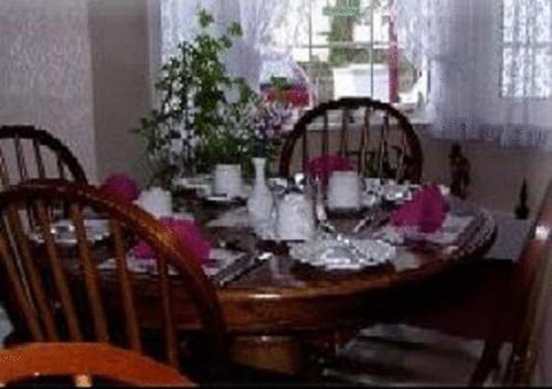 a dining room table with chairs and a wooden table with pink flowers at Dover's Restover Bed & Breakfast in Dover