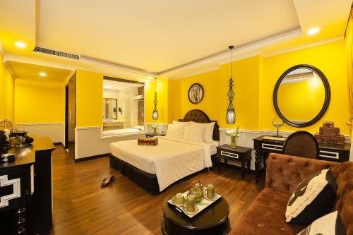 a bedroom with yellow walls and a bed and a couch at Adora Art Hotel in Ho Chi Minh City