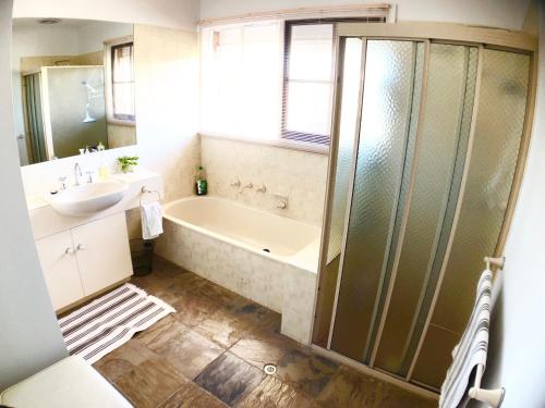 W łazience znajduje się wanna, umywalka i prysznic. w obiekcie Melbourne Garden Bed and Breakfast w mieście Melton