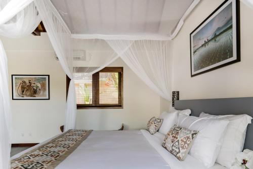 a white bedroom with a bed and a window at Villa Lotus in Nusa Lembongan