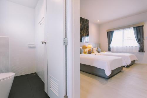 a white bedroom with two beds and a shower at Fantasy Hill Bungalow in Kata Beach