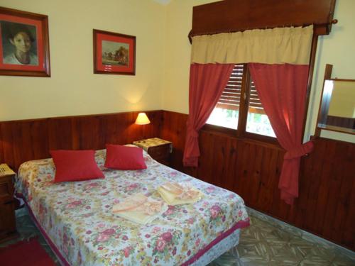 a bedroom with a bed with red pillows and a window at Hotel El Nogal in La Falda