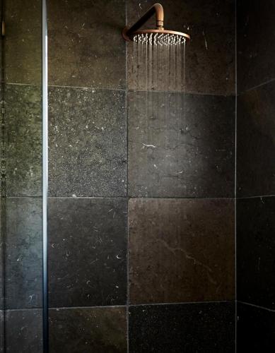 a shower with a shower curtain on a black tile floor at 28 Degrees Byron Bay - Adults Only in Byron Bay