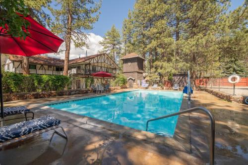 a swimming pool with a red umbrella next to a house at Black Forest Lodge in Big Bear Lake